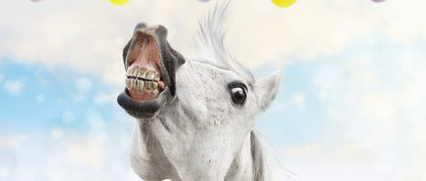 White horse runs to hanging Easter eggs on spring background 