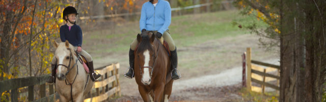 Caucasian girl and trainer riding horses 