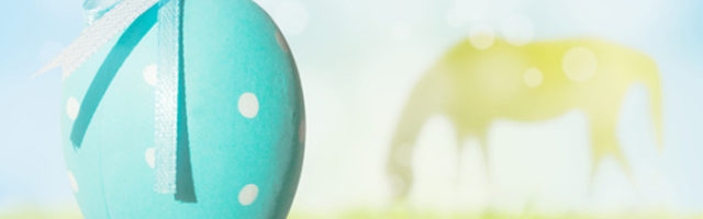 Easter egg hanging and silhouette of grazing horse 