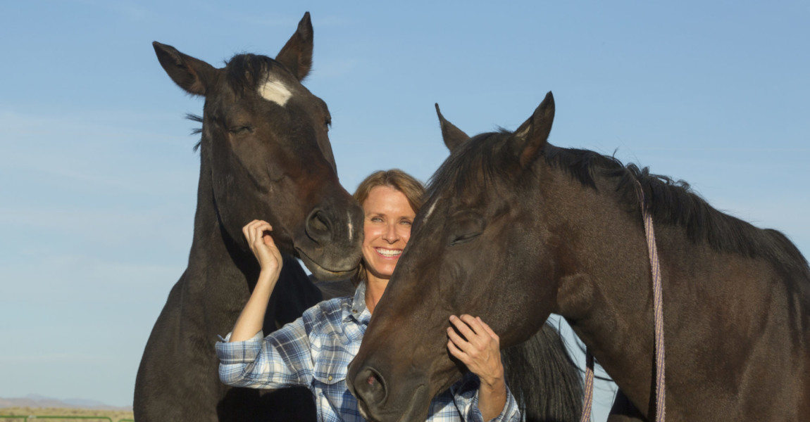 Caucasian rancher smiling with horses Caucasian rancher smiling with horses 